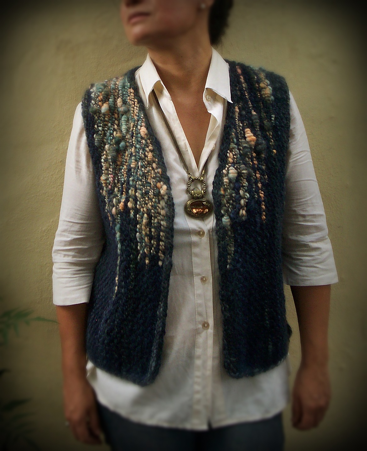 Person wearing handwoven pampa loom vest with art yarn and clasped weft technique of weaving saori style